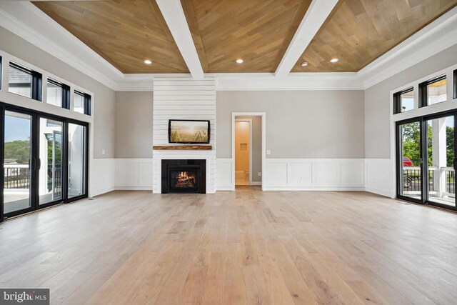 unfurnished living room with beam ceiling, a large fireplace, wood ceiling, and light hardwood / wood-style flooring