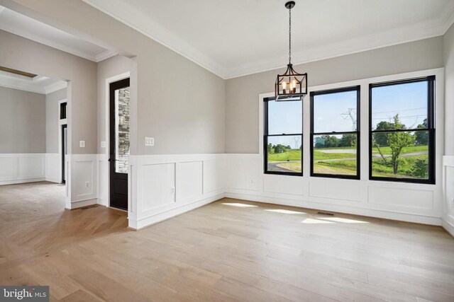 unfurnished dining area featuring ornamental molding, a chandelier, and light hardwood / wood-style flooring