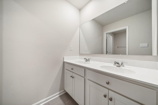 bathroom featuring double vanity, baseboards, and a sink