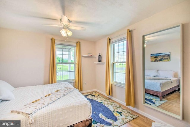 bedroom featuring baseboards, wood finished floors, and a ceiling fan