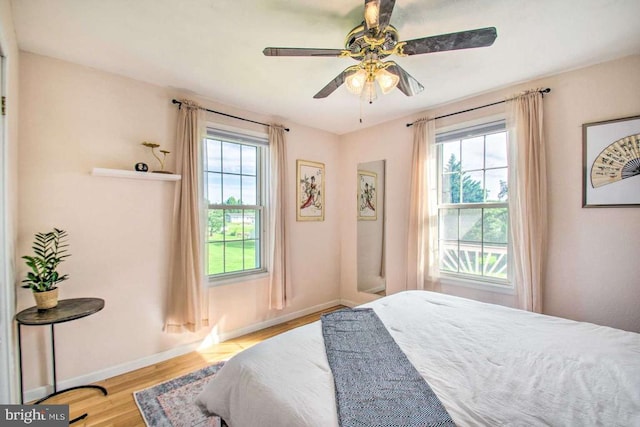 bedroom with multiple windows, baseboards, and wood finished floors