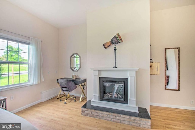 interior space featuring a glass covered fireplace, baseboards, and wood finished floors