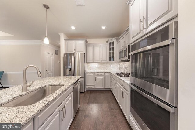 kitchen with sink, appliances with stainless steel finishes, hanging light fixtures, light stone counters, and white cabinets