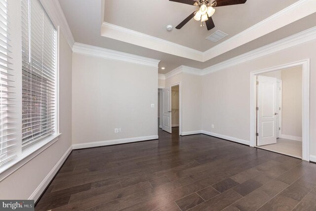 spare room featuring dark wood-type flooring, ceiling fan, crown molding, and a raised ceiling