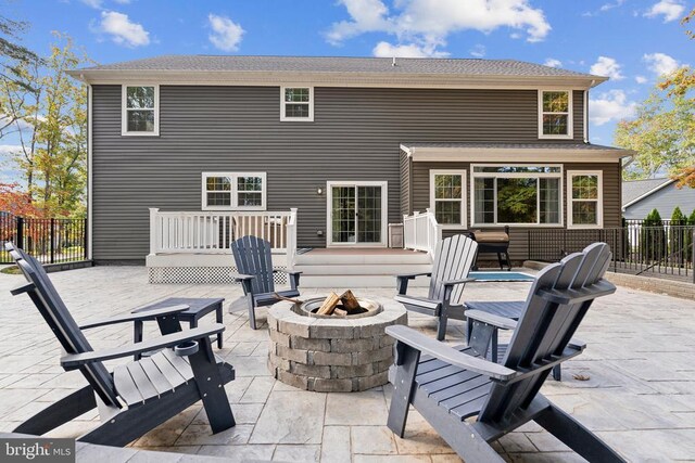 back of property with a patio area, fence, a deck, and an outdoor fire pit