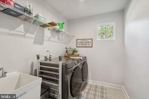 laundry room with washer and dryer, laundry area, baseboards, and a sink