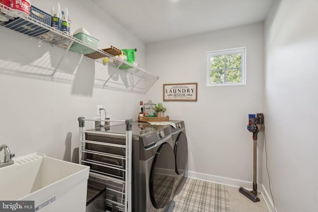 clothes washing area with laundry area, washing machine and dryer, baseboards, and a sink