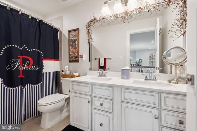 full bathroom with double vanity, toilet, tile patterned floors, and a sink