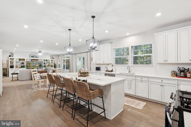 kitchen featuring gas range, white cabinets, a center island, and a sink