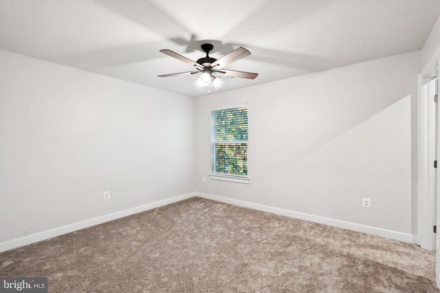 empty room with carpet flooring, a ceiling fan, and baseboards