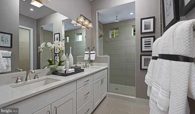 bathroom with tile patterned floors, vanity, and a tile shower