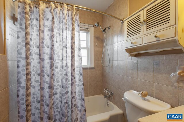 full bath featuring toilet, tile walls, and shower / tub combo with curtain