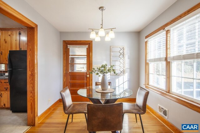 dining room with an inviting chandelier, light wood-style flooring, visible vents, and baseboards