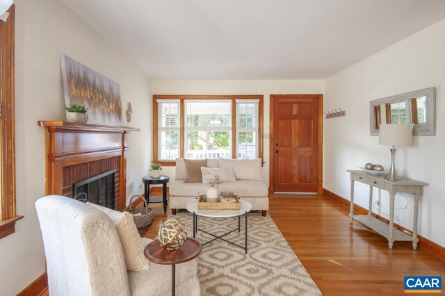 living room with a brick fireplace, baseboards, and wood finished floors