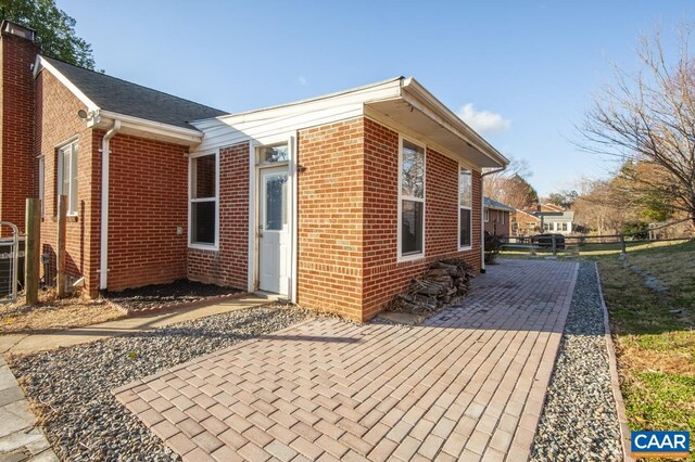 view of property exterior with a patio area, brick siding, and fence