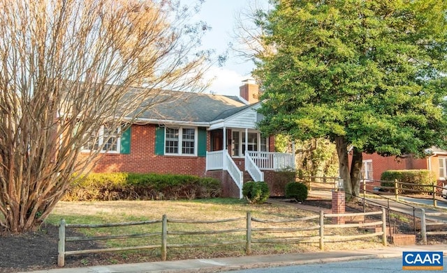 view of front of property featuring brick siding, a fenced front yard, a chimney, stairway, and a front yard