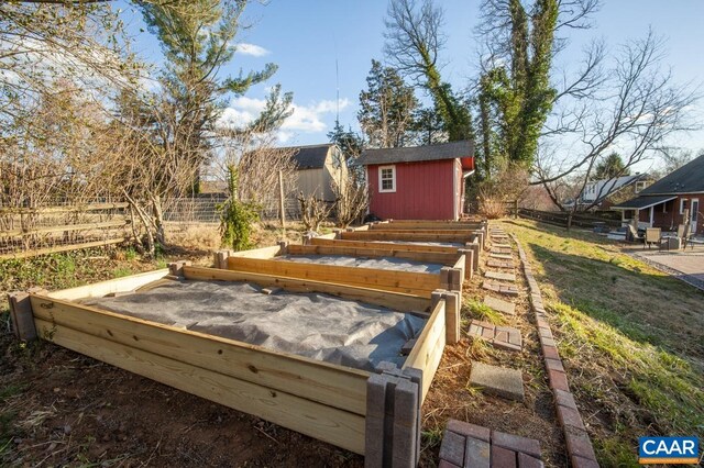 wooden deck featuring a storage unit, a garden, fence, and an outdoor structure