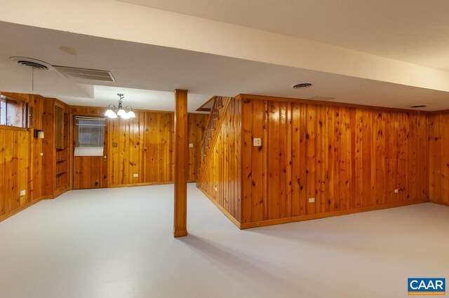 finished below grade area featuring stairs, wood walls, visible vents, and baseboards