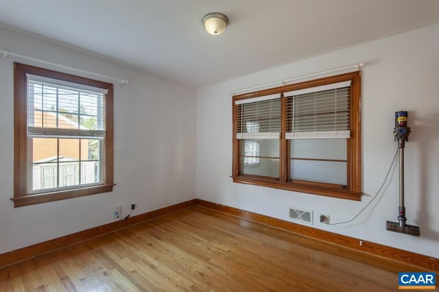 empty room with visible vents, light wood-style flooring, and baseboards