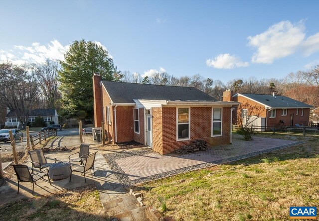 back of house with a patio, brick siding, a chimney, and fence