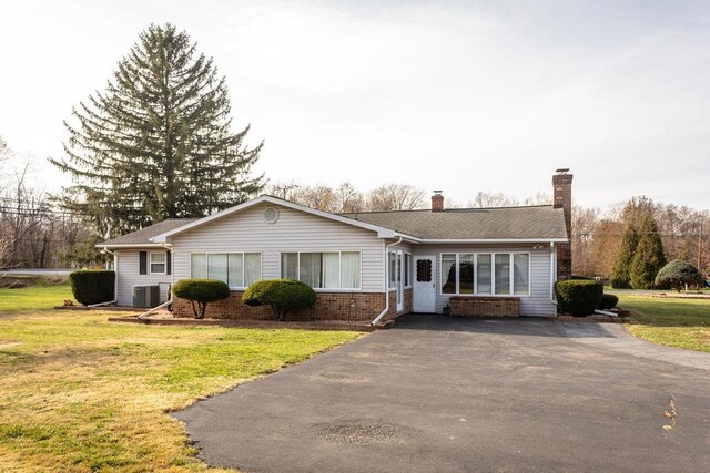 ranch-style house featuring cooling unit and a front lawn