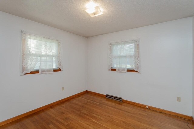 unfurnished room featuring wood-type flooring and a textured ceiling