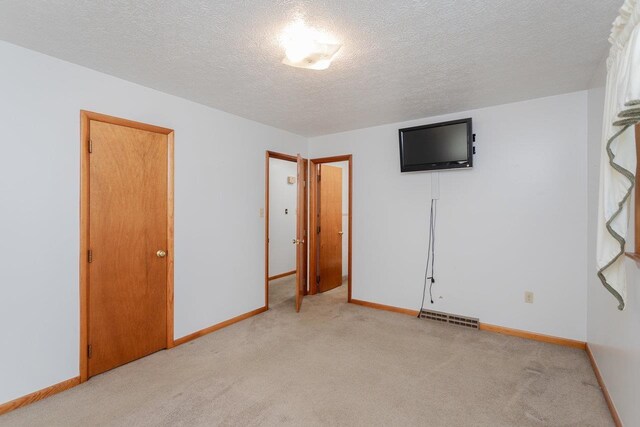 unfurnished bedroom with light carpet and a textured ceiling