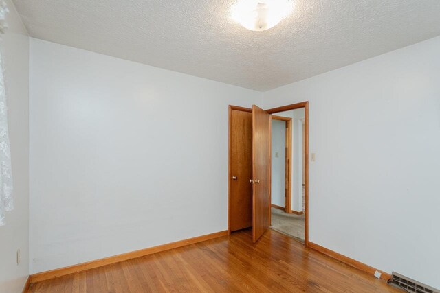 empty room featuring hardwood / wood-style flooring and a textured ceiling