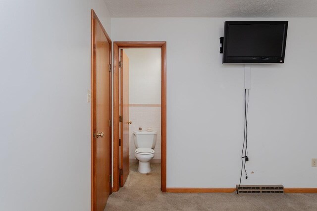 interior space featuring light carpet, a textured ceiling, and tile walls