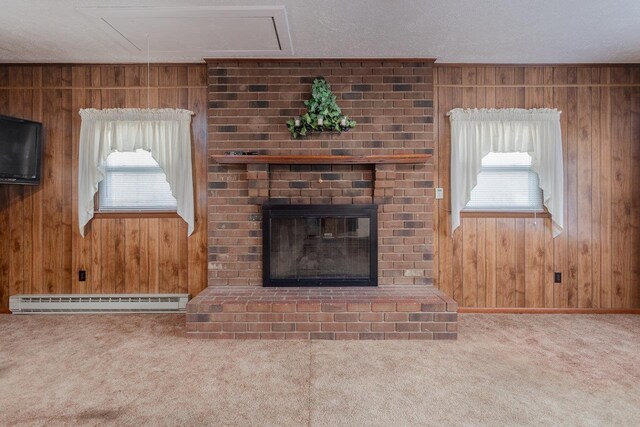 unfurnished living room with a baseboard heating unit, a brick fireplace, carpet floors, and plenty of natural light