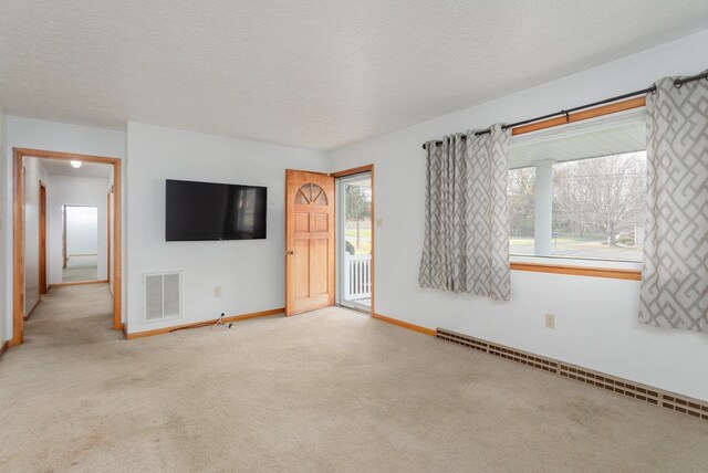 unfurnished living room with light carpet, a textured ceiling, and baseboard heating