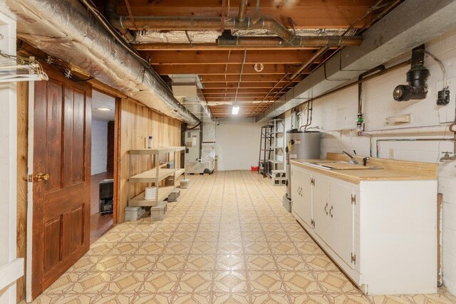 basement featuring heating unit, sink, and water heater