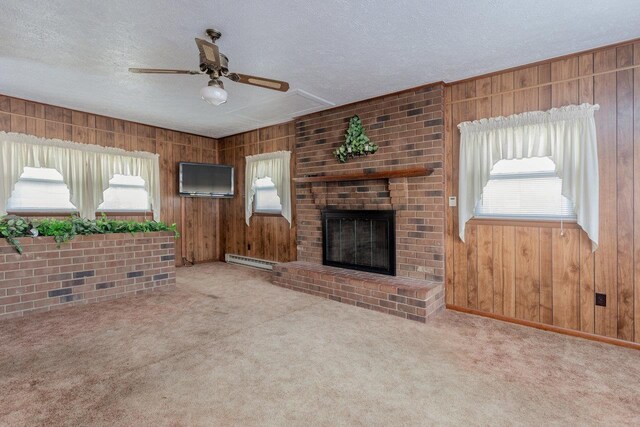 unfurnished living room with baseboard heating, light colored carpet, wooden walls, and a brick fireplace