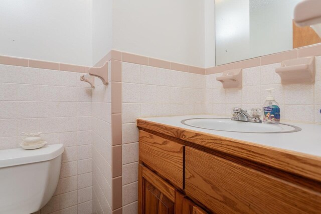 bathroom featuring vanity, tile walls, and toilet