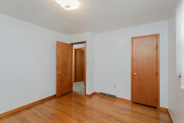 spare room with a textured ceiling and light wood-type flooring