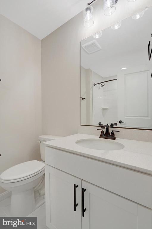 full bath with visible vents, a shower, toilet, marble finish floor, and vanity