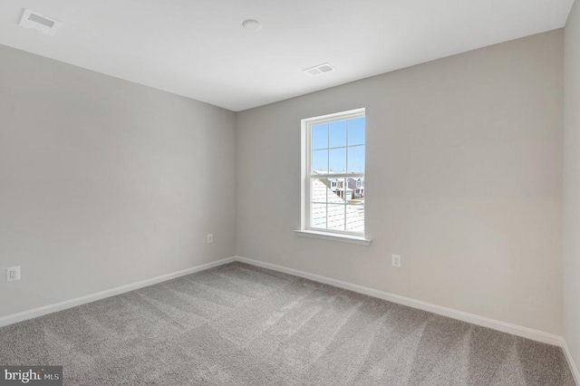 carpeted empty room featuring baseboards and visible vents