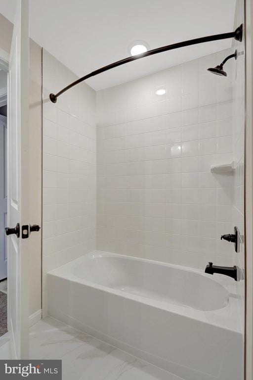 bathroom with marble finish floor and bathing tub / shower combination