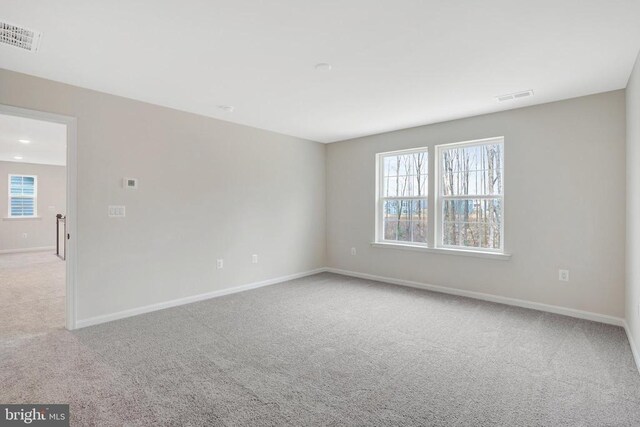 unfurnished room featuring light colored carpet, a healthy amount of sunlight, and visible vents