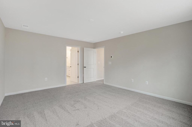 interior space featuring baseboards, connected bathroom, and light colored carpet