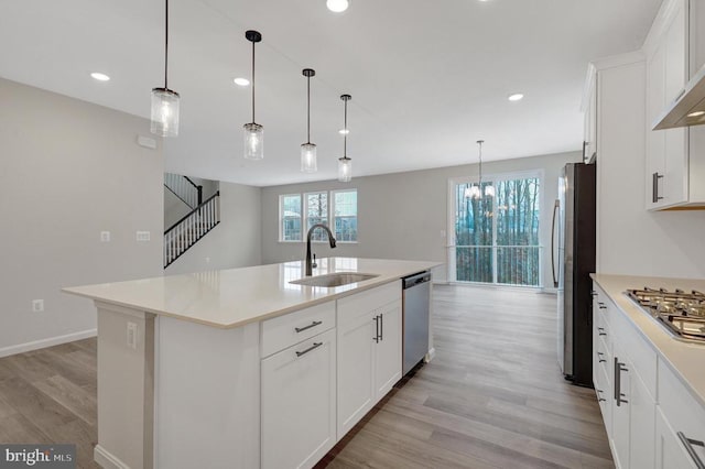 kitchen with an island with sink, stainless steel appliances, white cabinetry, and light countertops