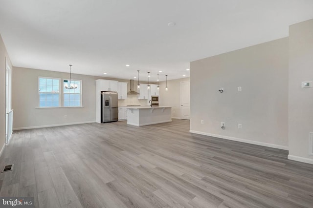 unfurnished living room featuring recessed lighting, visible vents, baseboards, light wood-type flooring, and an inviting chandelier