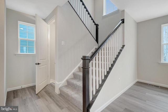 stairs with visible vents, baseboards, and wood finished floors