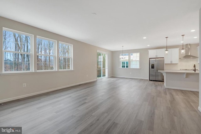 unfurnished living room with light wood finished floors, baseboards, a notable chandelier, and recessed lighting