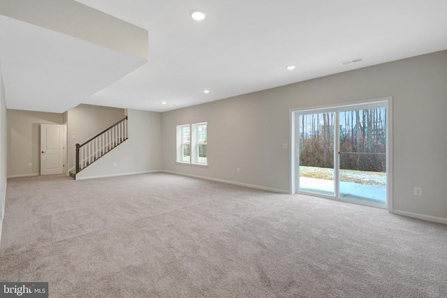 unfurnished living room featuring recessed lighting, visible vents, light colored carpet, stairway, and baseboards