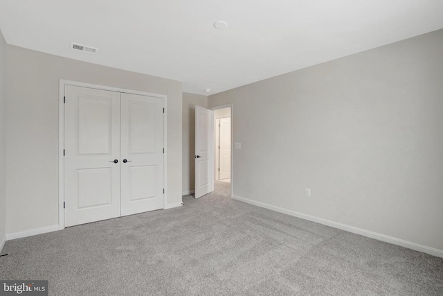 unfurnished bedroom with light colored carpet, a closet, visible vents, and baseboards