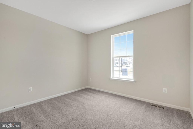 empty room featuring carpet floors, visible vents, and baseboards