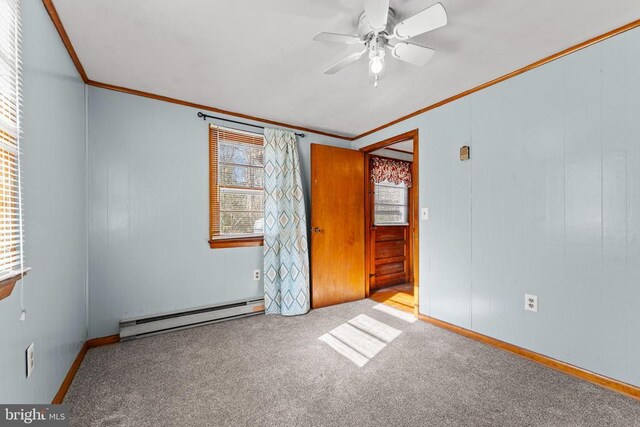 carpeted empty room featuring crown molding, ceiling fan, and baseboard heating