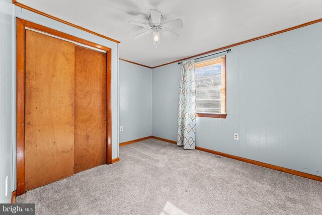 unfurnished bedroom with ornamental molding, light colored carpet, a closet, and ceiling fan