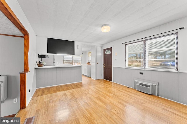 unfurnished living room with light hardwood / wood-style flooring and a wall mounted AC